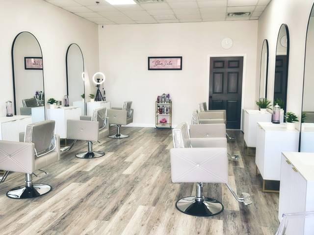 The salon floor: white stations, arched mirrors, blush chairs